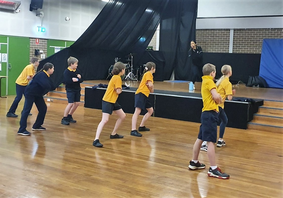Students learning dance moves in school hall