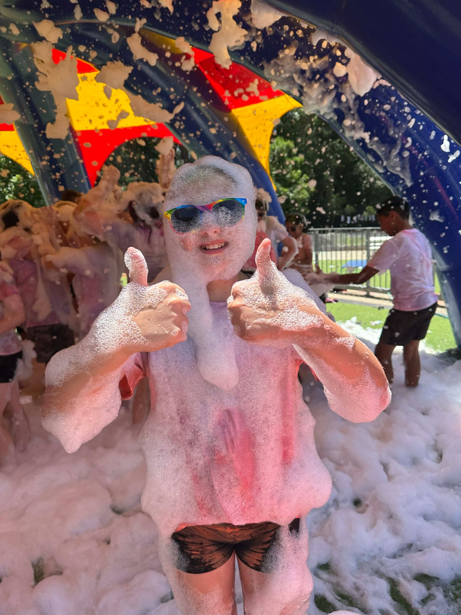 Kids covered in foam giving thumbs up inside foam dome